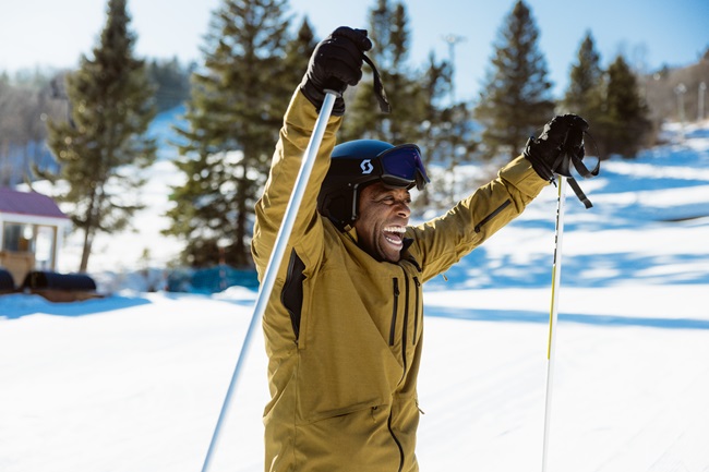 Un homme heureux en ski alpin lève ses bâtons dans les airs