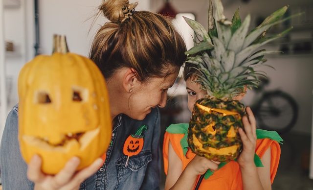 une mère et son fils montrent leur citrouille et ananas décorés pour l'halloween