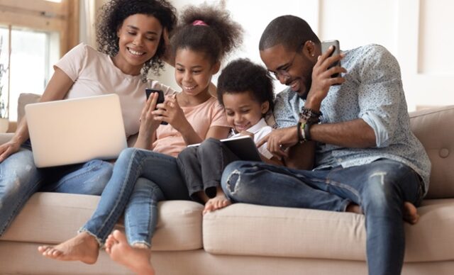 Happy addicted to gadgets black family using different devices.