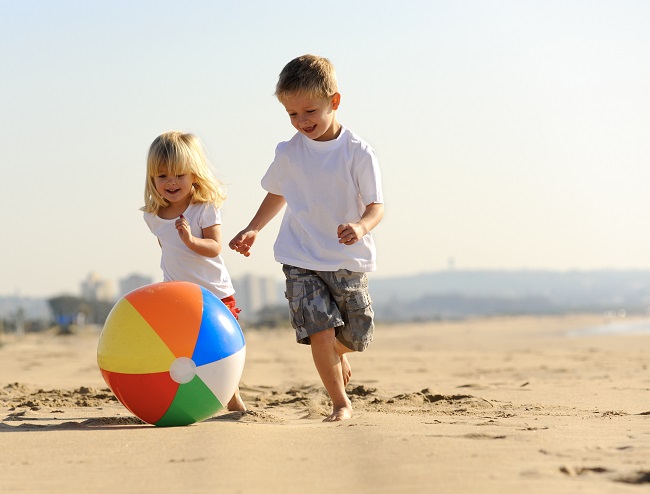 une fillette et un garcon jouent au ballon sur la plage