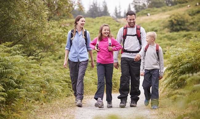 Jeune famille marchant sur un chemin de campagne pendant des vacances en camping en famille