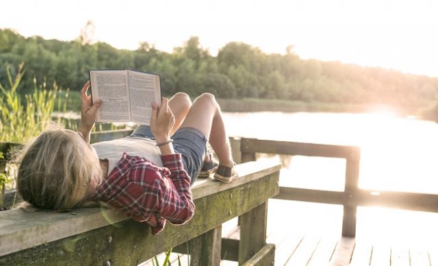 Jeune fille lisant un livre au bord du lac