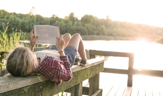 Jeune fille lisant un livre au bord du lac