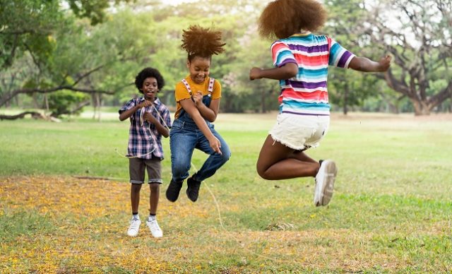 Groupe d'enfants afro-américains s'amusant à sauter par-dessus la corde dans le parc.