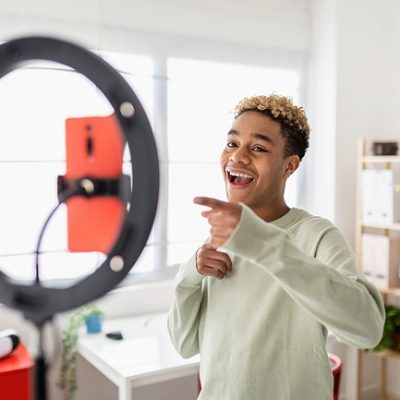 Jeune créateur masculin enregistrant une vidéo multimédia en ligne dans sa chambre