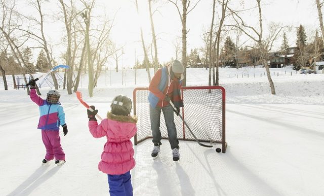 Father and daughters playing ice hockey