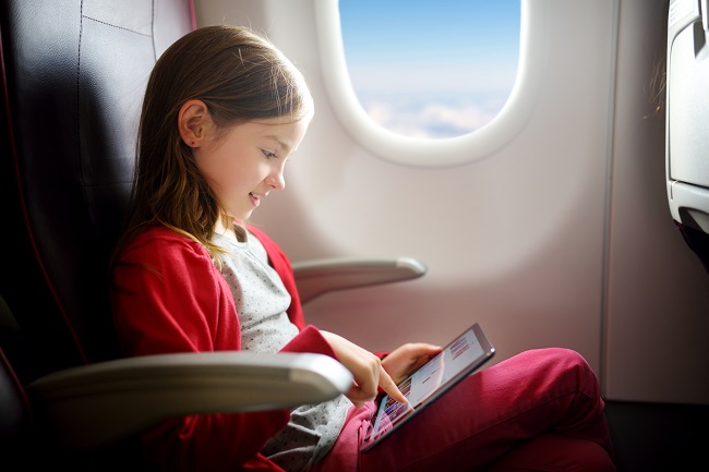 FiIlette qui regarde une tablette dans un avion