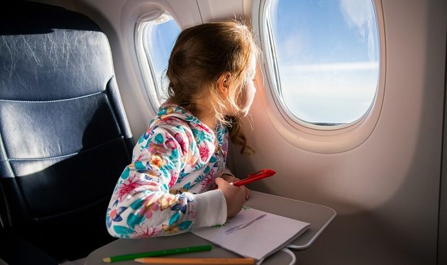 jeune fille qui regarde par le hublot d’un avion