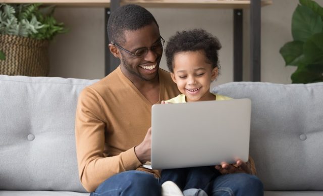 Smiling black dad and little son play computer game