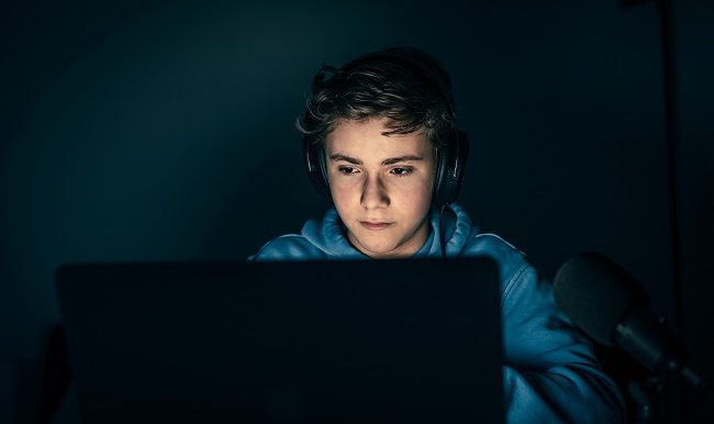 adolescent avec des écouteur joue à un jeu vidéo en ligne